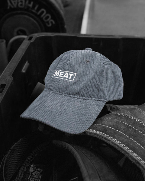 Gray corduroy baseball cap with embroidered MEAT logo, photographed in gym setting